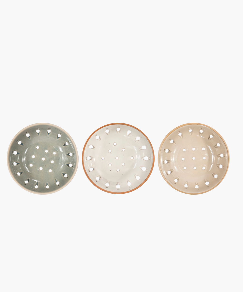 Three colanders in muted beige and gray tones are evenly spaced in a row. Each has a sleek, modern design with decorative cutout patterns. | Wildwood Home Co. 
