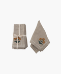 Two beige cloth napkins with orange floral embroidery. One stack is tied with a ribbon, the other folded open, suggesting elegance and simplicity. | Wildwood Home Co.